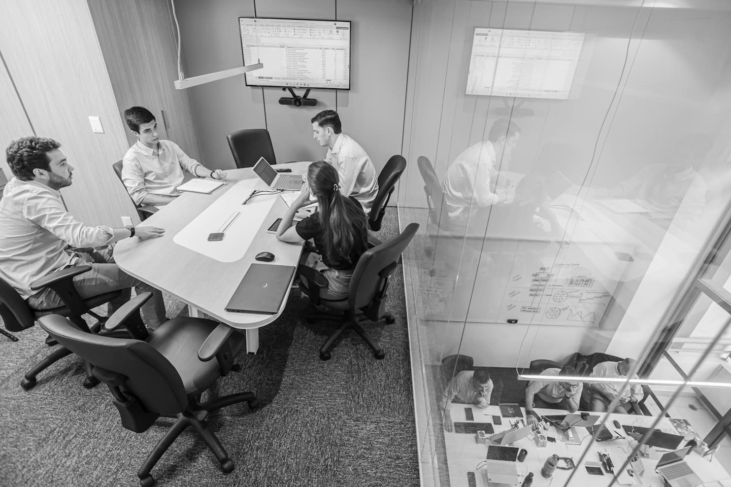 Contact Professionals collaborate around a conference table with laptops and a spreadsheet.