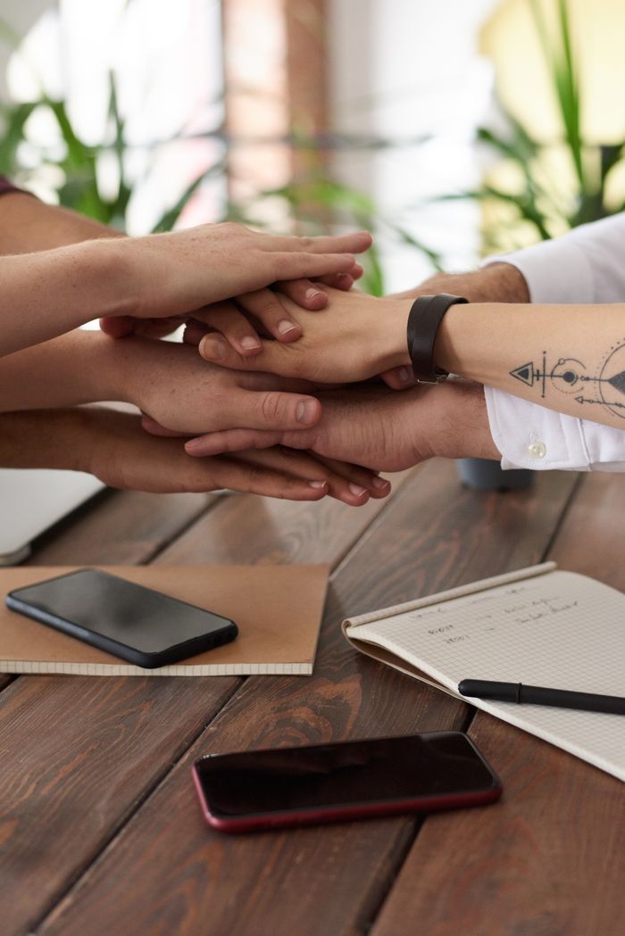 Services Hands from a diverse team stack on a table symbolizing unity and teamwork in a modern office setting.