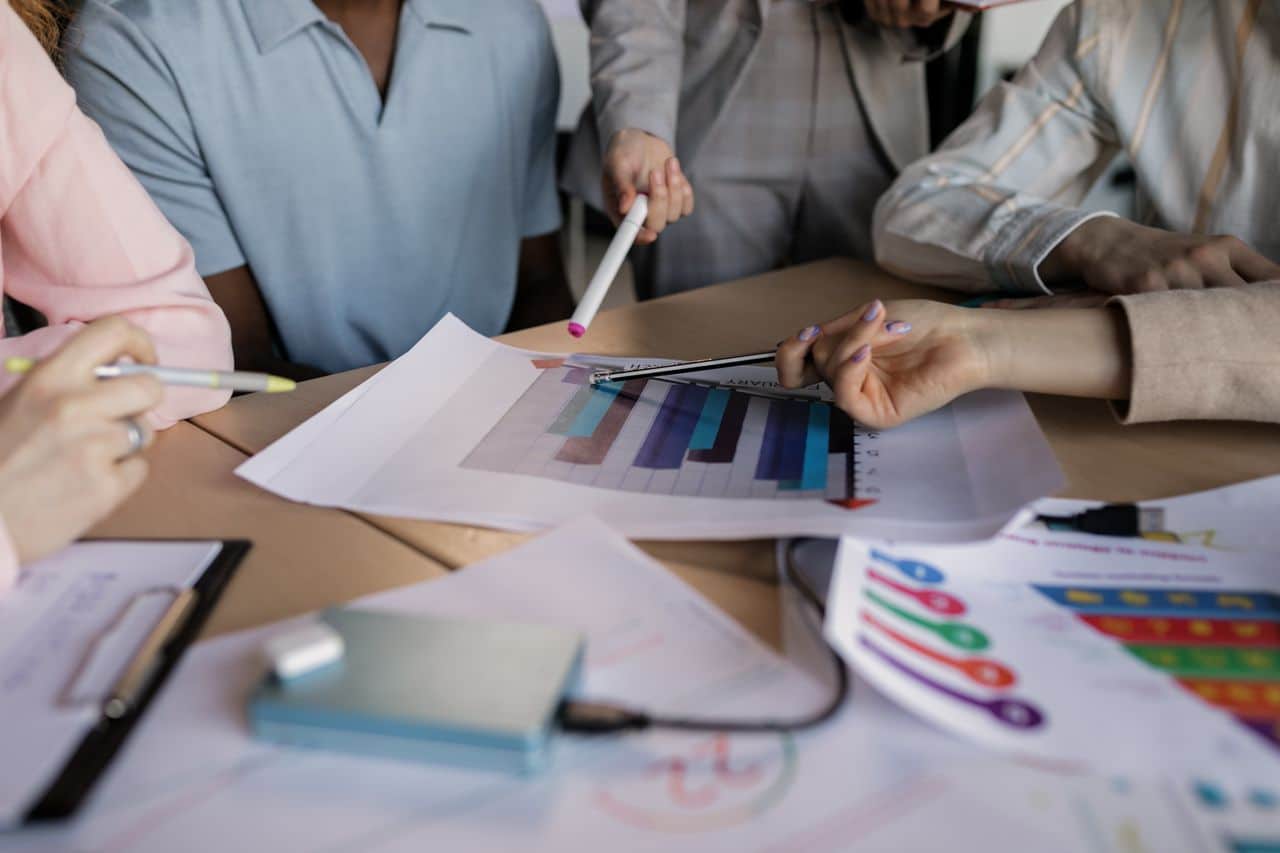 Services A diverse team engaged in planning and discussing a business strategy around a wooden table indoors.