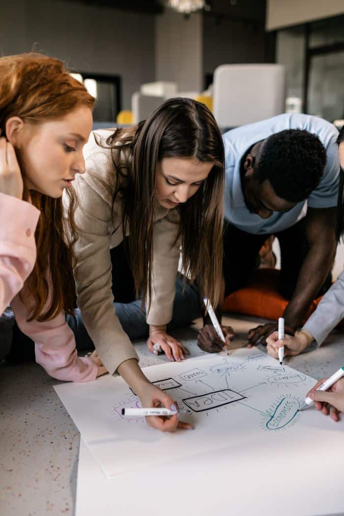 Services Colleagues gather around a paper, brainstorming creative ideas for a small business strategy.